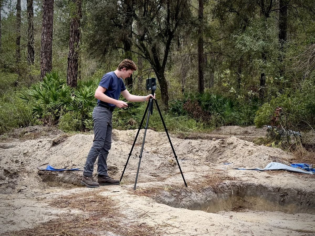 Setting up a scanner on a tripod at a wooded site